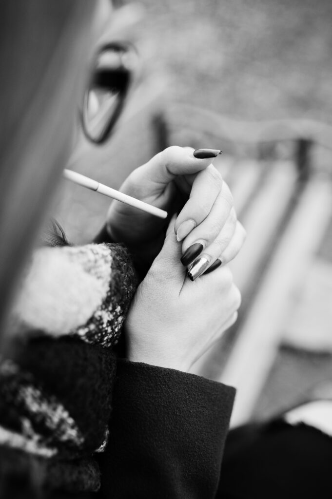 young girl lighting cigarette outdoors close up. concept of nico